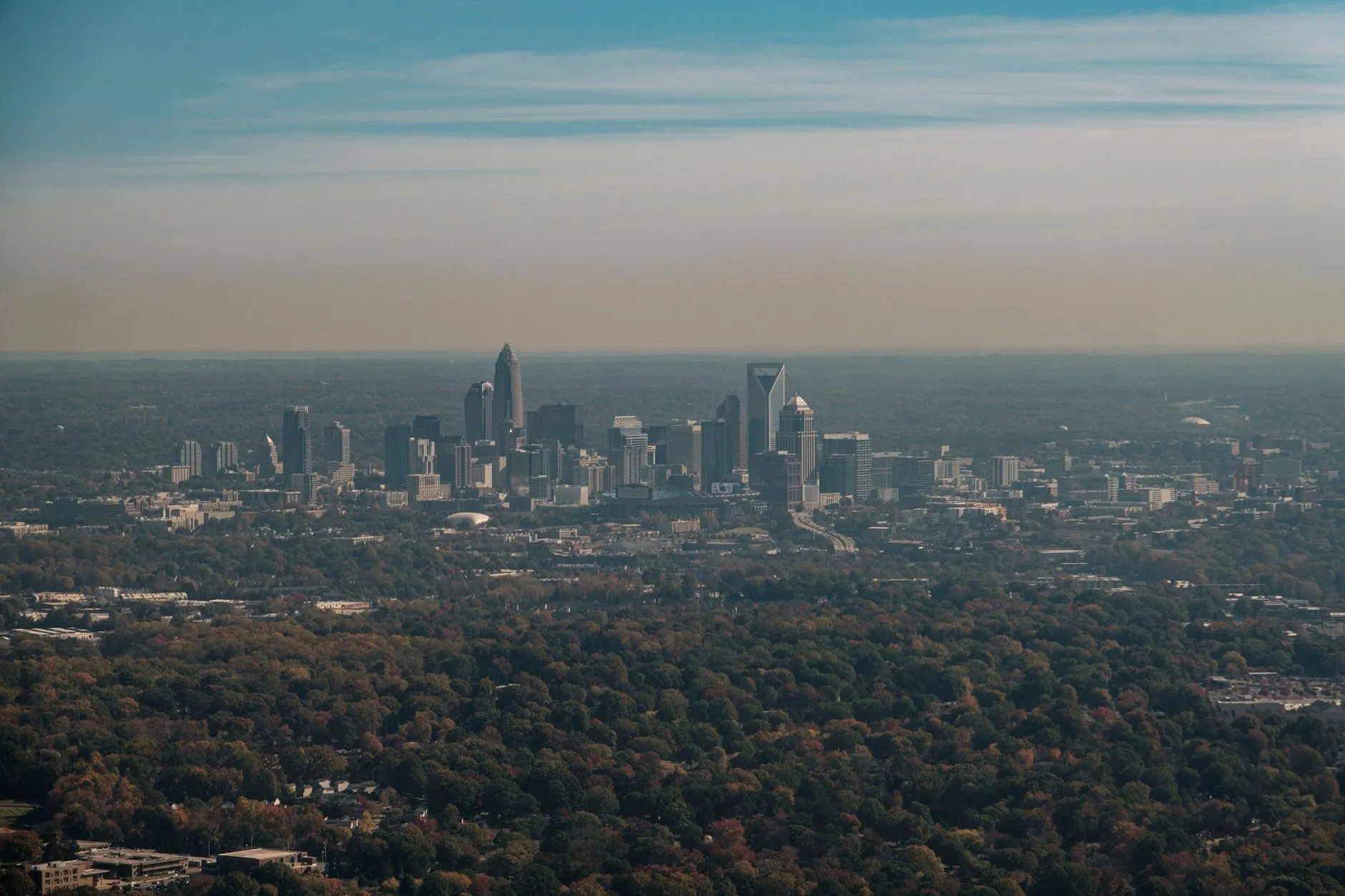 An aerial view of the Charlotte skyline surrounded by autumn trees