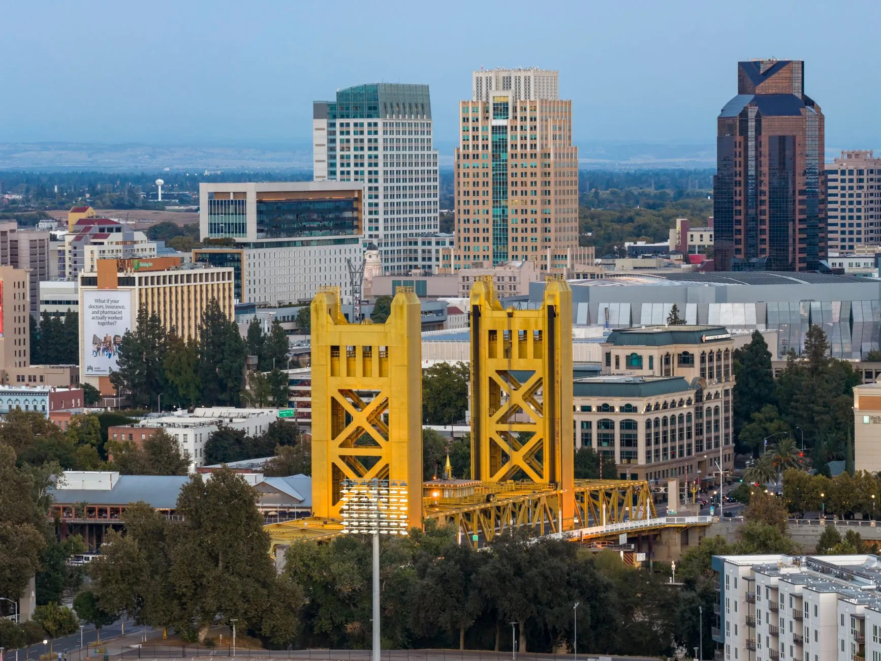 Sacramento's golden Tower Bridge over the river, with the downtown towers rising behind it in clear evening light
