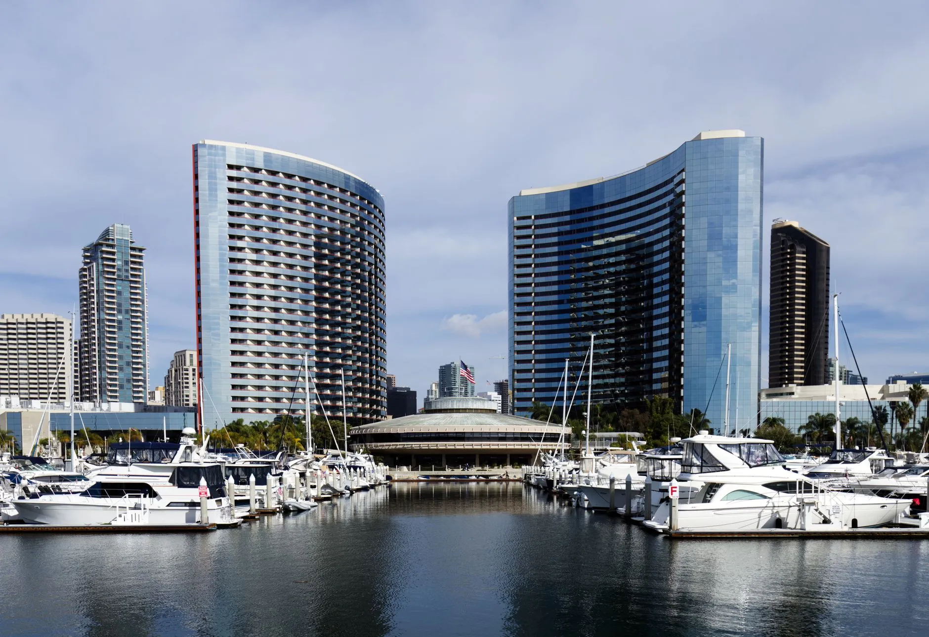 Yachts moored in the San Diego marina below the curved twin towers of the Marriott Marquis and the domed roof of the Convention Center.