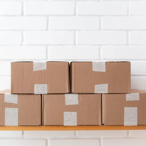 Cardboard moving boxes taped shut and stacked on a shelf